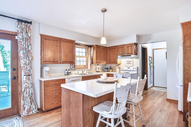 kitchen with white appliances, a sink, light countertops, and light wood finished floors