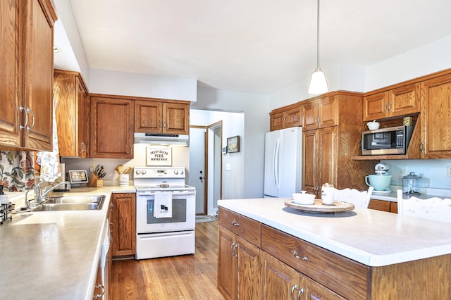 kitchen with white appliances, exhaust hood, a sink, brown cabinets, and light countertops