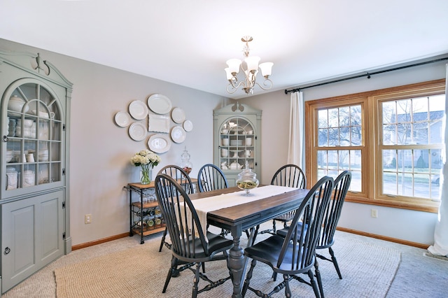 dining area featuring a chandelier, light carpet, and baseboards
