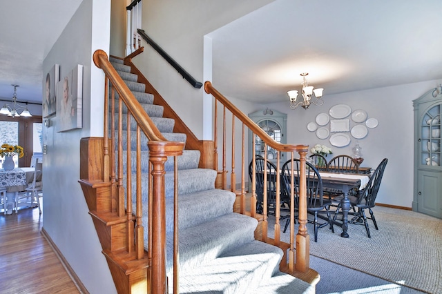 stairs with a chandelier, baseboards, and wood finished floors