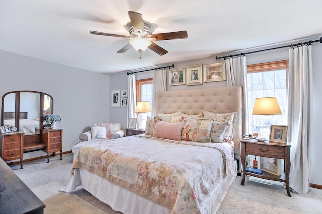 bedroom with multiple windows, light carpet, a ceiling fan, and baseboards