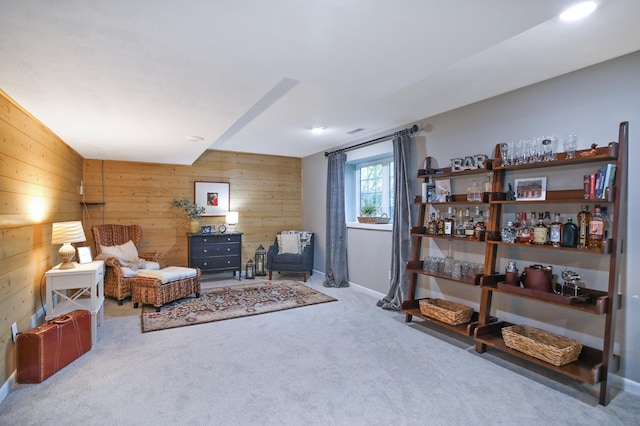 living area with wooden walls, carpet, and baseboards