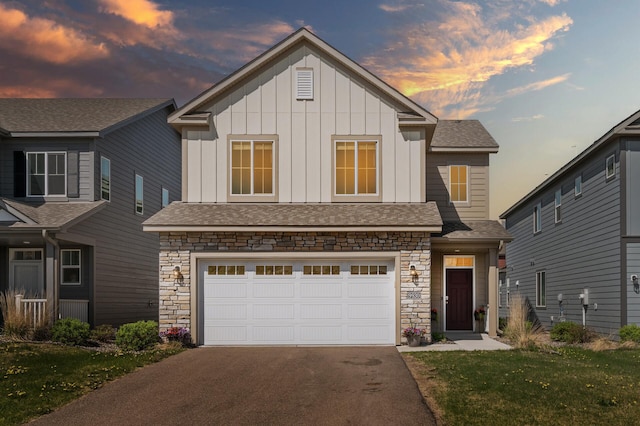 view of front facade with stone siding, driveway, a garage, board and batten siding, and a shingled roof