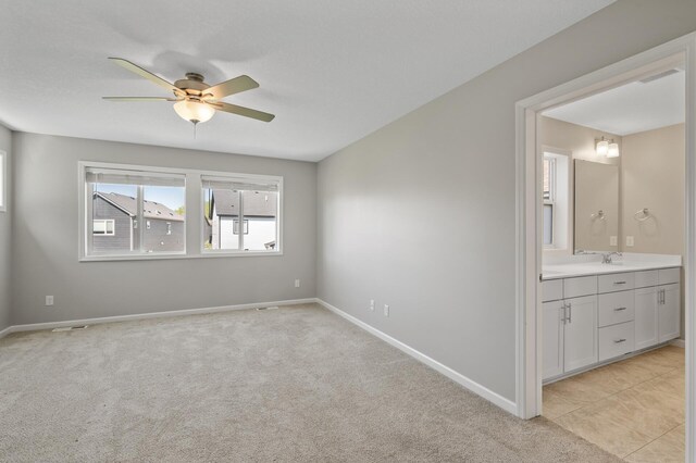 spare room featuring a sink, a ceiling fan, and baseboards