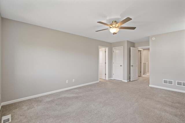 empty room featuring baseboards, ceiling fan, and light carpet