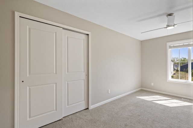 unfurnished bedroom with carpet flooring, baseboards, a closet, and ceiling fan