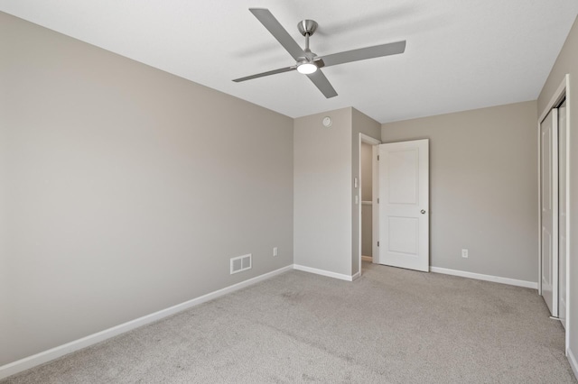 unfurnished bedroom with carpet flooring, baseboards, a closet, and a ceiling fan