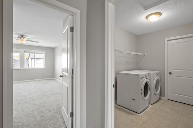 clothes washing area with a textured ceiling, washing machine and clothes dryer, ceiling fan, baseboards, and light tile patterned floors