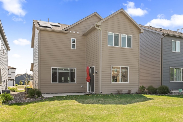 rear view of property featuring solar panels, a lawn, and central AC