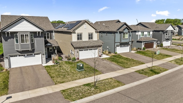 view of front facade with stone siding, driveway, an attached garage, and a residential view