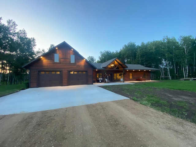 log home with driveway, a lawn, a porch, and an attached garage