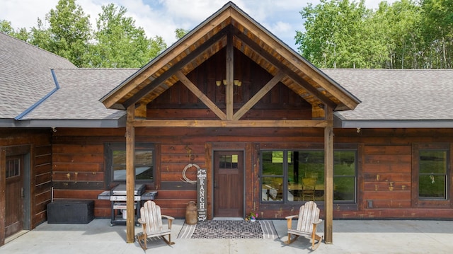 property entrance featuring a shingled roof and a patio