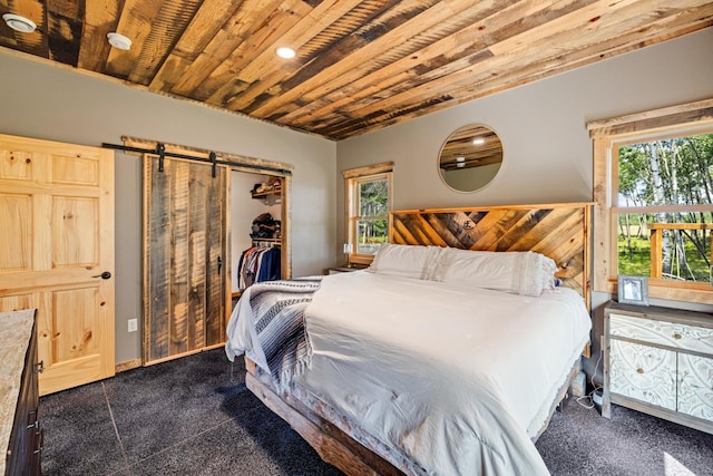 bedroom with dark carpet, a barn door, wood ceiling, and multiple windows