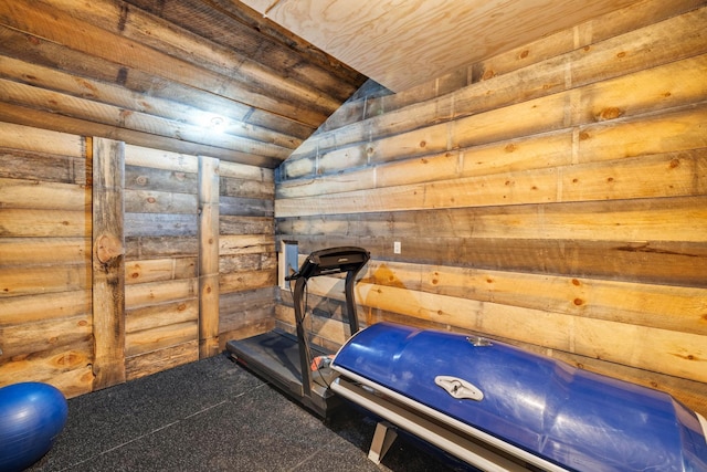 exercise room with vaulted ceiling, wooden walls, and carpet floors