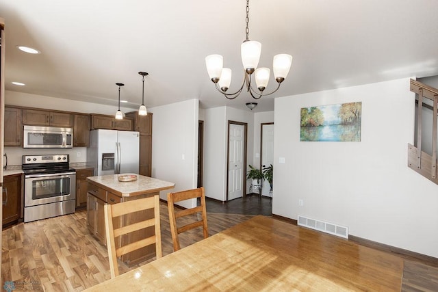 kitchen featuring stainless steel appliances, light countertops, a center island, light wood-type flooring, and recessed lighting