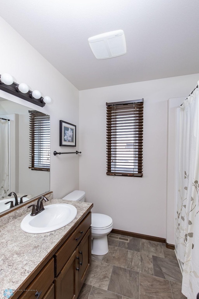 bathroom with vanity, toilet, and baseboards
