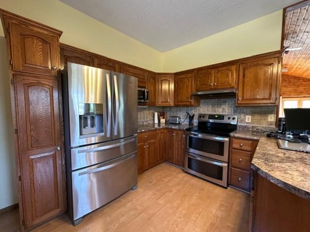 29441 108th St NW, Princeton, MN 55371 - kitchen with appliances with stainless steel finishes, light wood-style flooring, brown cabinetry, and decorative backsplash