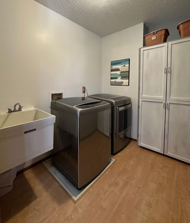 29441 108th St NW, Princeton, MN 55371 - laundry area with cabinet space, light wood-style floors, a textured ceiling, and washer and clothes dryer