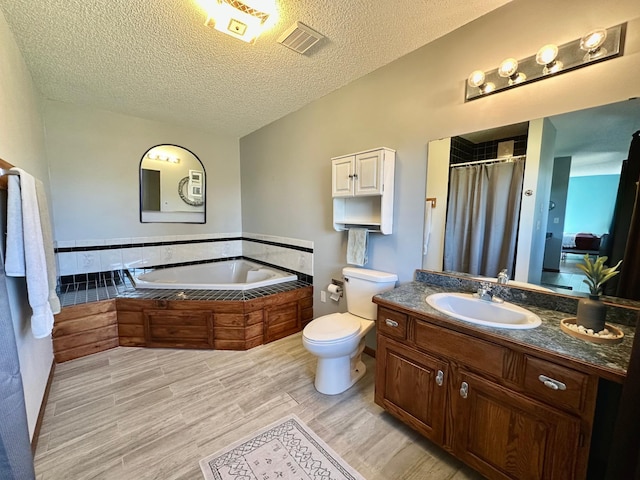 29441 108th St NW, Princeton, MN 55371 - bathroom featuring a textured ceiling, wood finished floors, toilet, vanity, and a garden tub