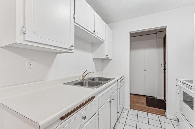 kitchen with a sink, white cabinets, light countertops, white appliances, and light tile patterned flooring