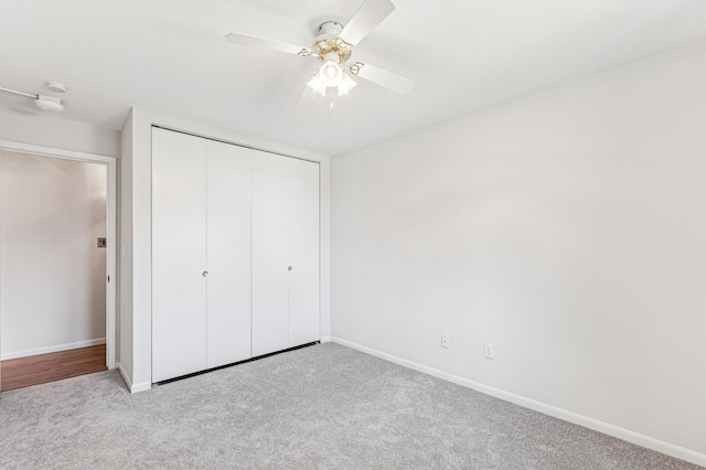 unfurnished bedroom featuring carpet flooring, a closet, baseboards, and ceiling fan