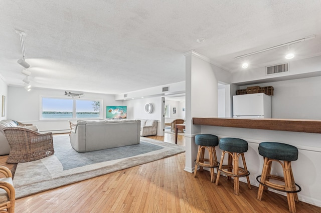 living room with track lighting, a textured ceiling, and hardwood / wood-style floors