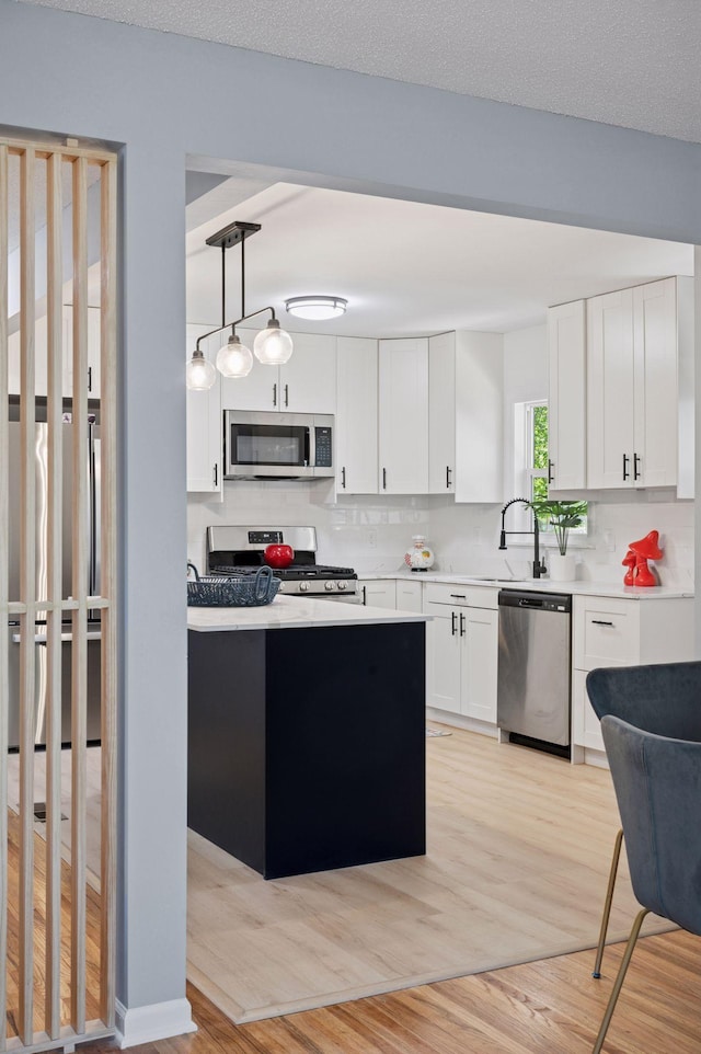 3544 Lee Ave N, Crystal, MN 55422 - kitchen with stainless steel appliances, tasteful backsplash, white cabinetry, light wood-style floors, and light countertops