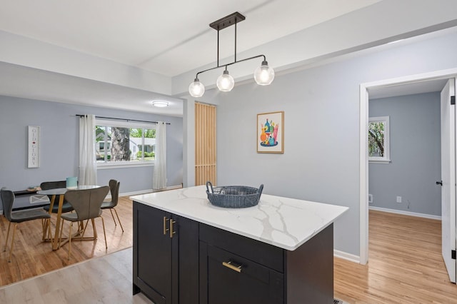 3544 Lee Ave N, Crystal, MN 55422 - kitchen with dark cabinetry, light wood-style flooring, pendant lighting, a center island, and light stone countertops