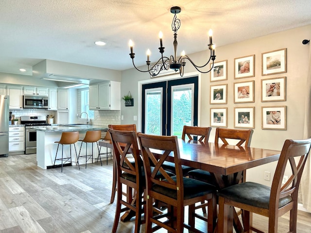 dining room featuring light wood finished floors, a textured ceiling, a chandelier, and recessed lighting
