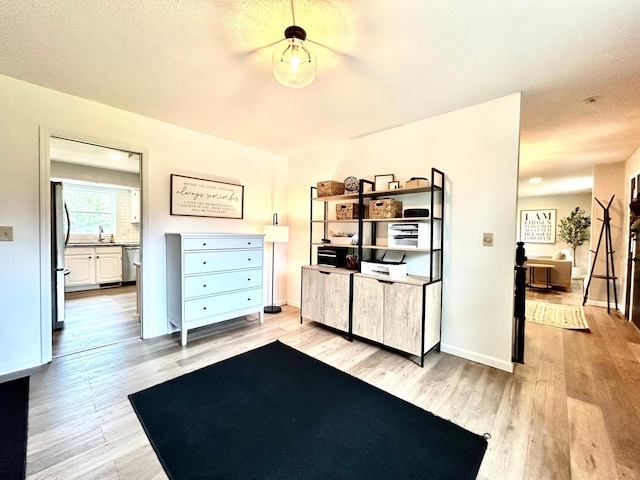 workout room featuring light wood finished floors, baseboards, and a sink