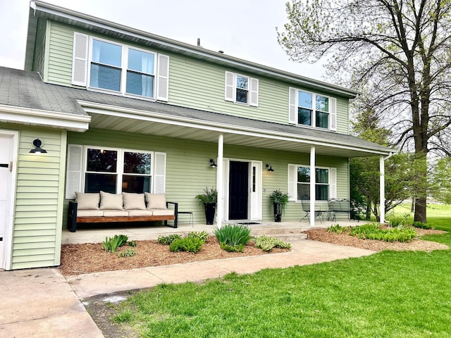 traditional-style house featuring covered porch, a front lawn, and outdoor lounge area