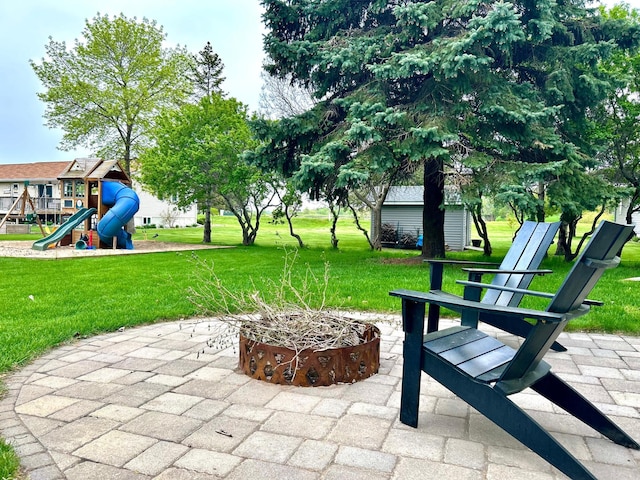 view of community featuring a playground, a yard, and a patio area