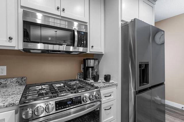38760 Maple Ct, North Branch, MN 55056 - kitchen with appliances with stainless steel finishes, white cabinetry, light stone counters, and wood finished floors