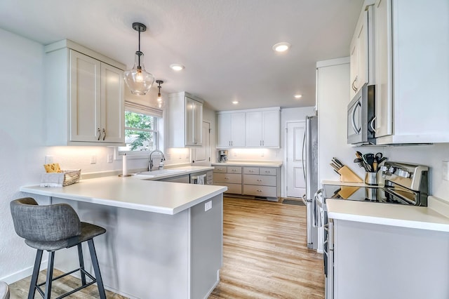 26533 Paradise Point Rd, Detroit Lakes, MN 56501 - kitchen featuring appliances with stainless steel finishes, a sink, a peninsula, light wood-style flooring, and a breakfast bar area