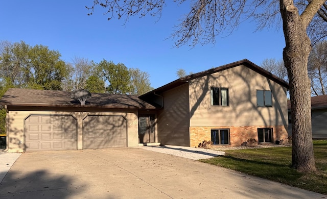 split level home featuring an attached garage, concrete driveway, brick siding, and a front lawn