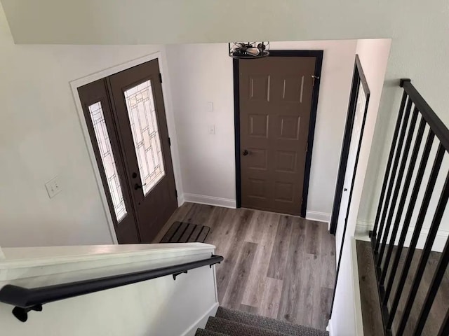 foyer entrance featuring wood finished floors, stairway, and baseboards