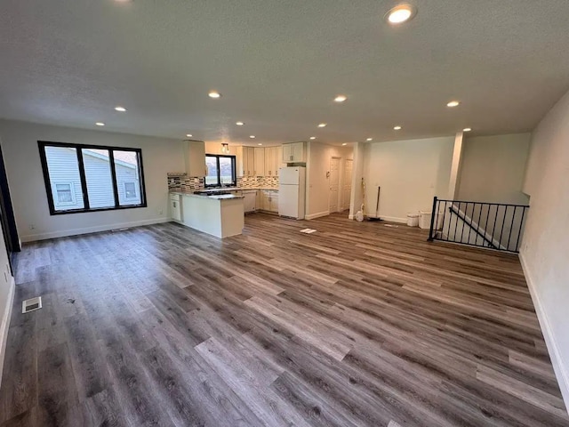 unfurnished living room featuring recessed lighting, dark wood-style floors, baseboards, and a textured ceiling