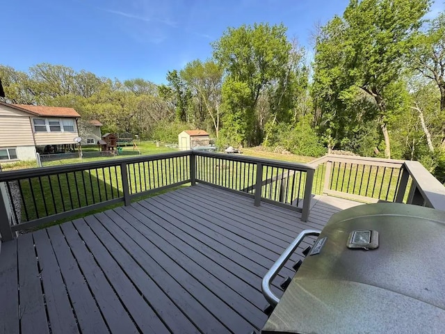 deck with a storage shed, an outdoor structure, a playground, and area for grilling