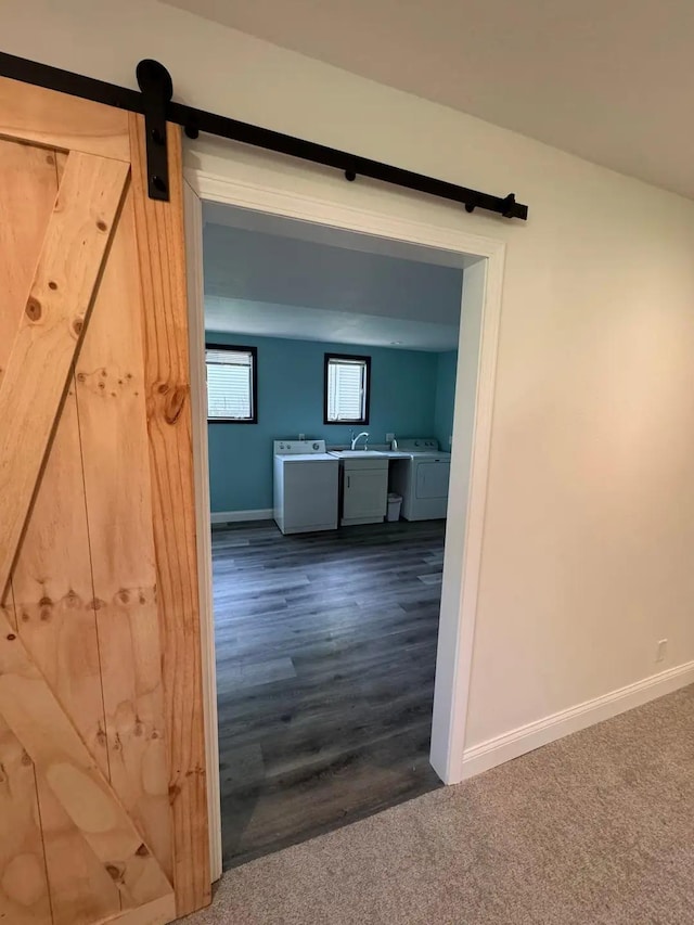 hallway featuring washer and dryer, a barn door, baseboards, and a sink