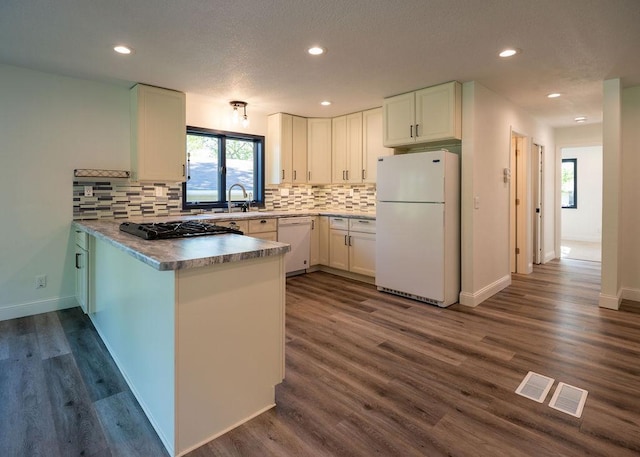 408 19th St NW, Willmar, MN 56201 - kitchen with white appliances, a peninsula, healthy amount of natural light, decorative backsplash, and recessed lighting