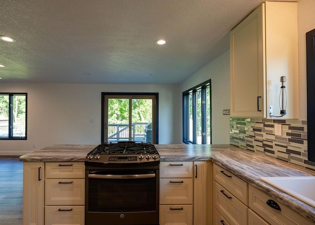 408 19th St NW, Willmar, MN 56201 - kitchen with stainless steel gas range oven, a textured ceiling, a peninsula, plenty of natural light, and recessed lighting