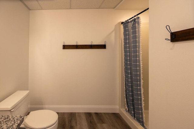 408 19th St NW, Willmar, MN 56201 - full bath with wood finished floors, toilet, a drop ceiling, a shower with curtain, and baseboards