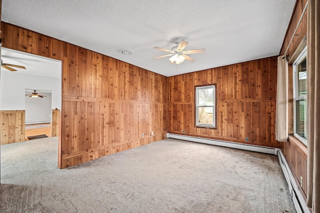 444 Vincent St, Saint Croix Falls, WI 54024 - carpeted empty room featuring a ceiling fan, wooden walls, a baseboard heating unit, a textured ceiling, and baseboard heating
