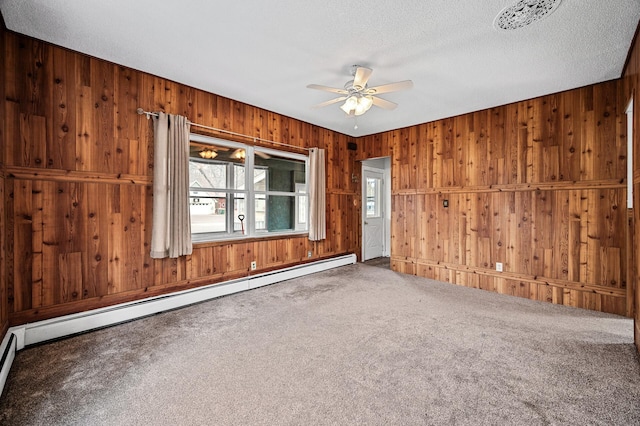 444 Vincent St, Saint Croix Falls, WI 54024 - empty room with a baseboard radiator, carpet floors, ceiling fan, wood walls, and a textured ceiling
