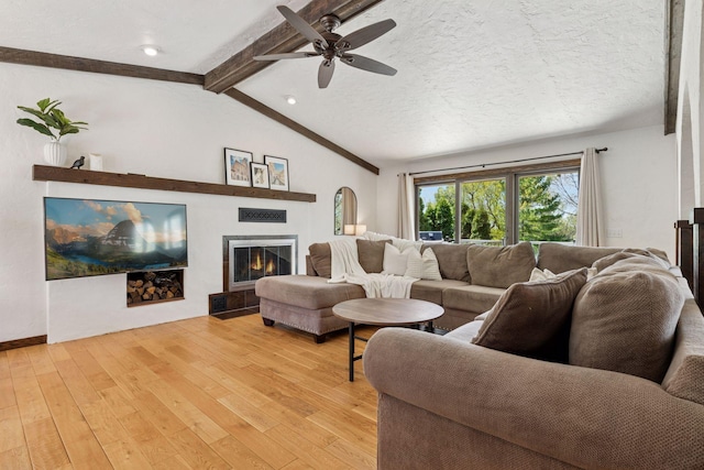 living room with light wood-type flooring, ceiling fan, and a glass covered fireplace
