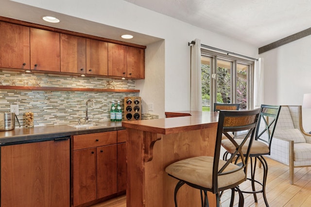 indoor wet bar with light wood-style flooring, decorative backsplash, and recessed lighting