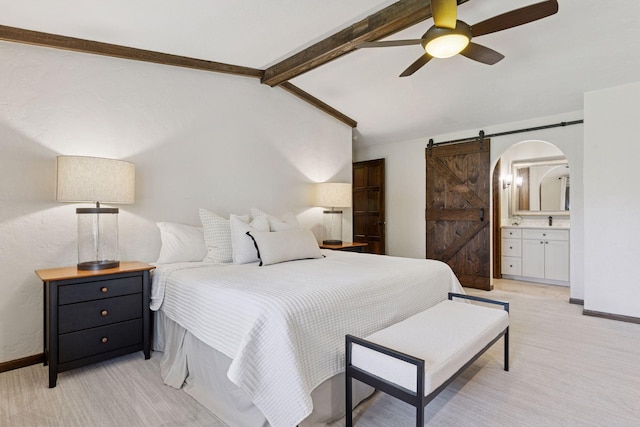 bedroom featuring a barn door, arched walkways, light colored carpet, ensuite bathroom, and baseboards