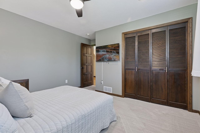 bedroom featuring a closet, light colored carpet, baseboards, and ceiling fan