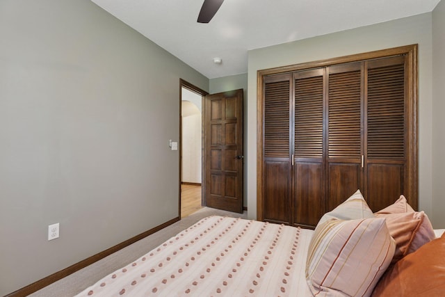 carpeted bedroom featuring a closet, baseboards, and a ceiling fan