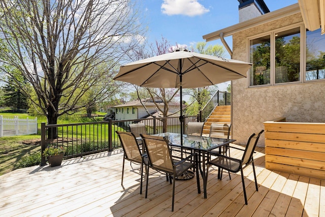 wooden deck with outdoor dining area, stairway, and fence